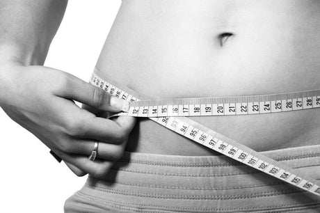 Black and white picture of a women measuring her tummy.