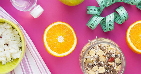 Bird's eye view that show a bowl of muesli and cottage cheese as well as half an orange, a water bottle and a measuring tape.