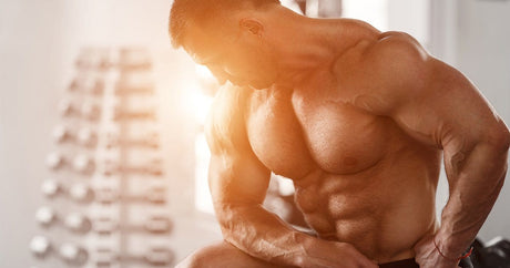 Muscular men looking down at his naked upper body.