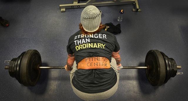 Back view of a guy who lifts a barbell