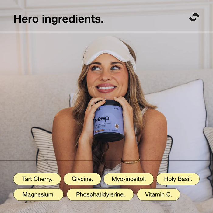 Woman holding a container of 'Sleep' supplement with a sleep mask on, surrounded by pillows.