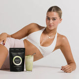 Woman in white active wear sitting with a 'Beauty Match' product and a drink on a white background